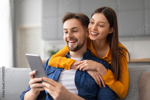 Joyful spouses engaged with digital tablet on the couch
