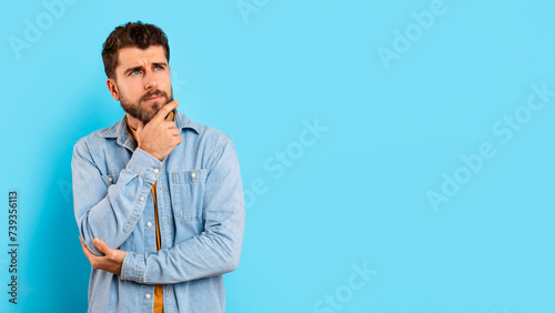 Portrait of thoughtful millennial man looking aside at copy space