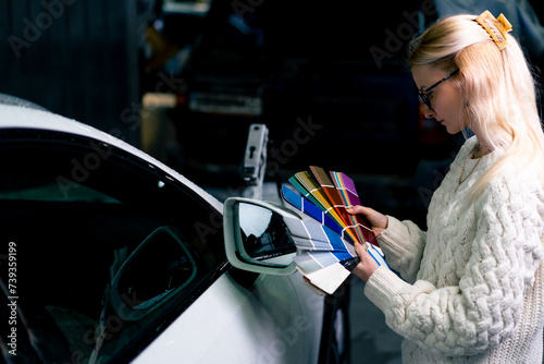 girls at the service station choose the paint color of white car on a color paper palette