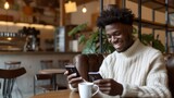 Smiling man using two smartphones in a cafe