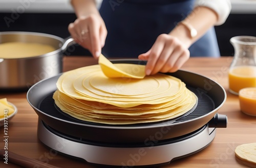 Woman cooking delicious crepe on electrical pancake maker in kitchen
