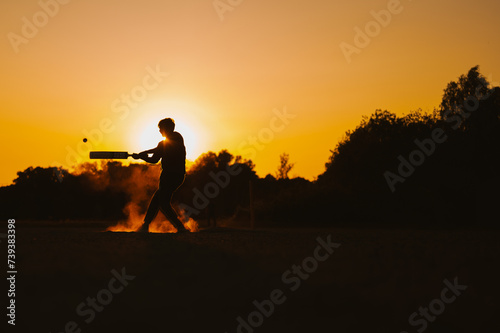 Silhouette of a person playing cricket in a sunset