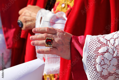 hand of the cardinal with a showy cassock ring with red ruby during the blessing of the faithful at the end of the mass photo