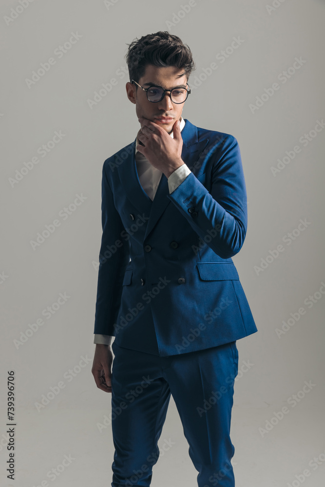 thoughtful young businessman in blue suit touching chin and thinking thoughtful young businessman in blue suit touching chin and thinking