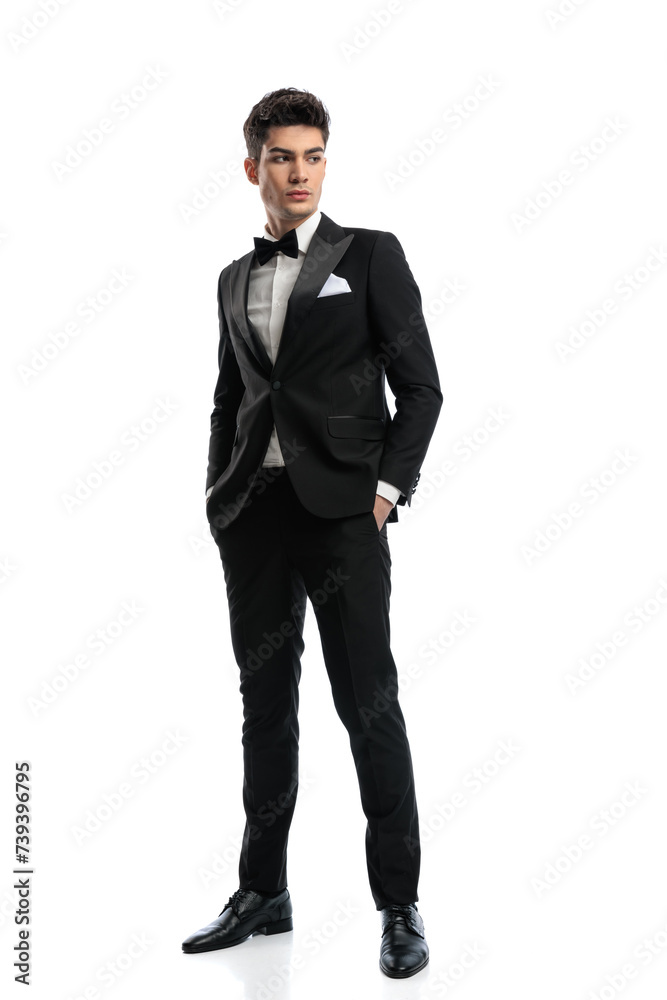 confident young man in black tuxedo holding hands in pockets confident young man in black tuxedo holding hands in pockets