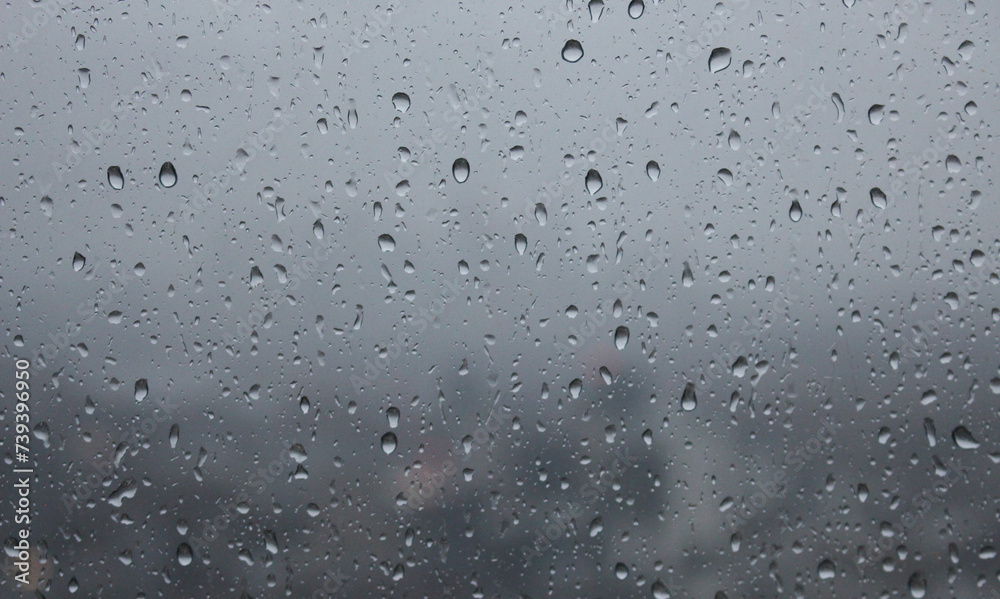 A close up photograph of raindrops on a window, looking out over an urban cityscape at dusk. Evening on a grey and cloudy day. A close up photograph of raindrops on a window, looking out over an urban cityscape at dusk. Evening on a grey and cloudy day.
