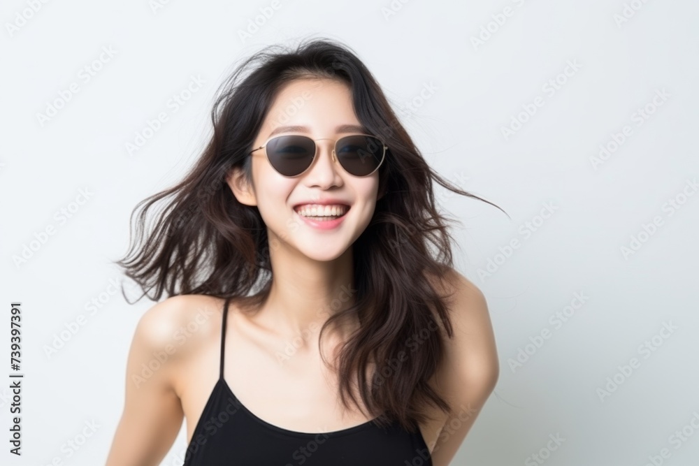Cheerful young woman in a black top with fashionable round sunglasses, joyful pose.