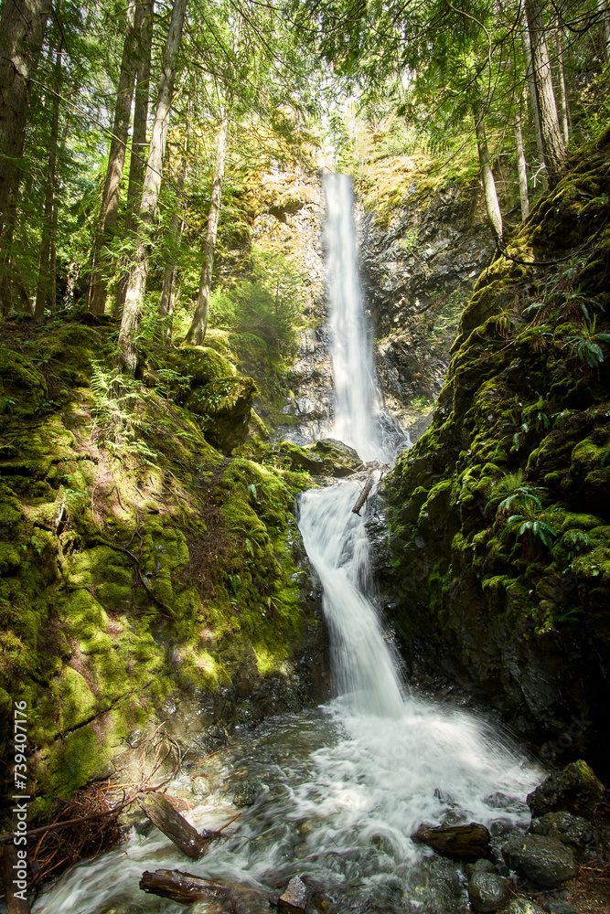 View of a majestic, tall waterfall cascading down the mountain side. View of a majestic, tall waterfall cascading down the mountain side.
