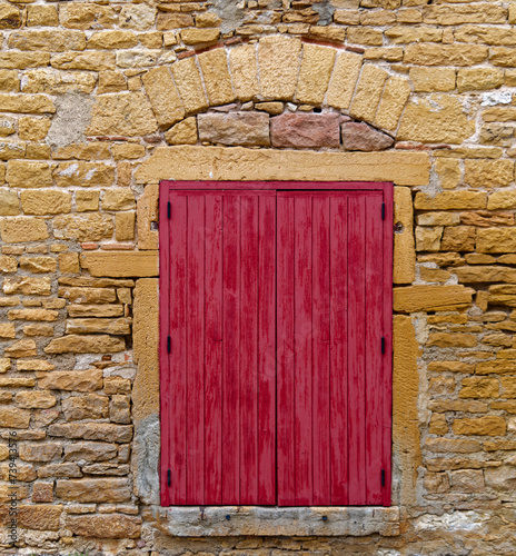 Old closed wood window shutters on a wall of golden stones (aka Couzon stones) in Beaujolais, France