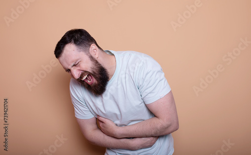 A man touching his stomach on beige background with copy space. Stomach pain and others stomach disease concept. © lashkhidzetim