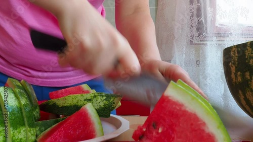 Female hands cutting fresh juicy watermelon slices. Watermelon Citrullus lanatus is a flowering plant species of the Cucurbitaceae family and the name of its edible fruit. Cooking. Cutting fruit. photo