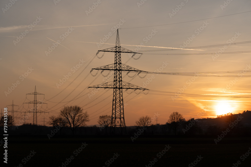 Silhouette of powerlines with the red glowing sun in the evening