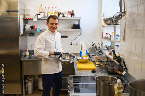 Smiling young chef preparing food in a restaurant kitchen