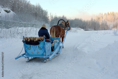 A horse team with a beautiful sleigh and a coachman in a sheepskin coat. A Horse Drawn Sleigh Ride Through The Snow. A horse pulled by a sleigh to transport passengers. photo