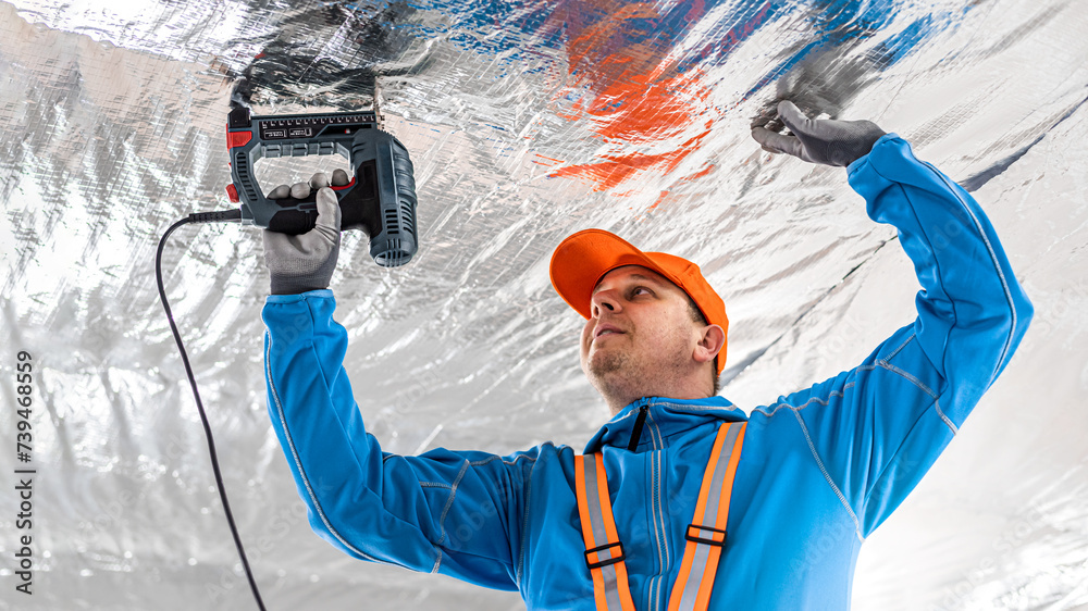 The builder is fastening the vapor barrier under the ceiling thermal insulation using an