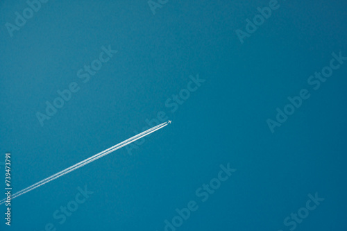Looking up at a jet and contrail against a blue sky.