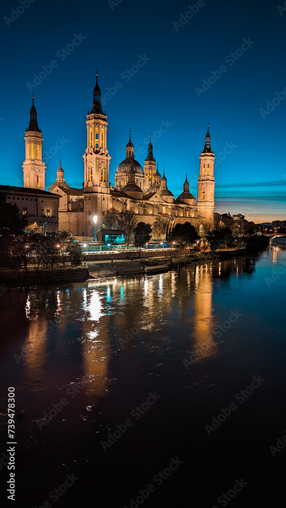 As the Sun Bids Farewell and the Ebro River Turns into a Mirror: The Enchantment of Sunset Facing the Iconic Basilica of Our Lady of the Pillar in Zaragoza