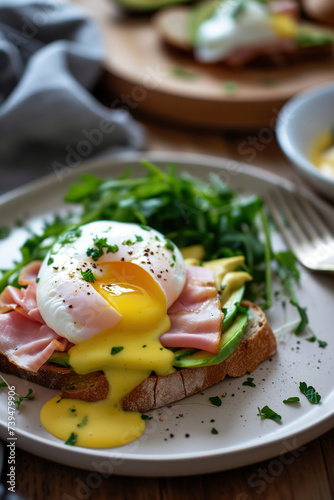 Poached eggs with ham, avocado and arugula on toast 