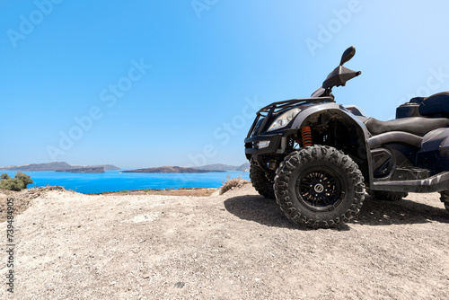 Quad bike parked on the seafront of the Akrotiri peninsula in the southwestern part of the island of Santorini with a view of the volcanic caldera of Nea Kameni.  photo