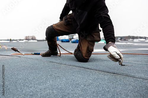 Valokuva professional roofer applying bitumen roll on flat roof with a gas burner at a mo