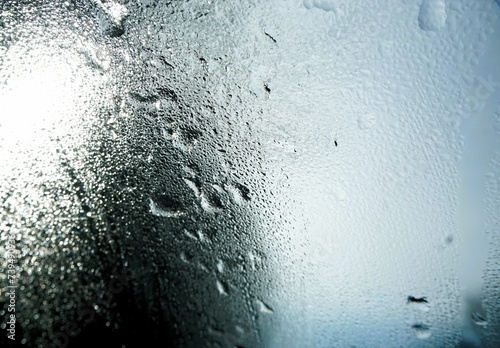 Abstraktes Motiv mit Wassertropfenmuster vor grau-weißem Himmel mit weißer Sonne bei Nebel, Sonne, Frost und Regen am morgen im Winter photo