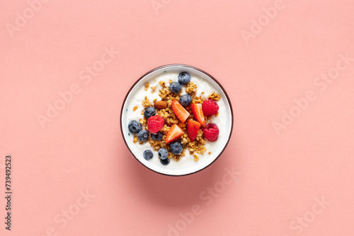 Healthy breakfast bowl with ingredients granola fruits Greek yogurt and berries on a pink background top view. Weight loss, healthy lifestyle and eating concept photo