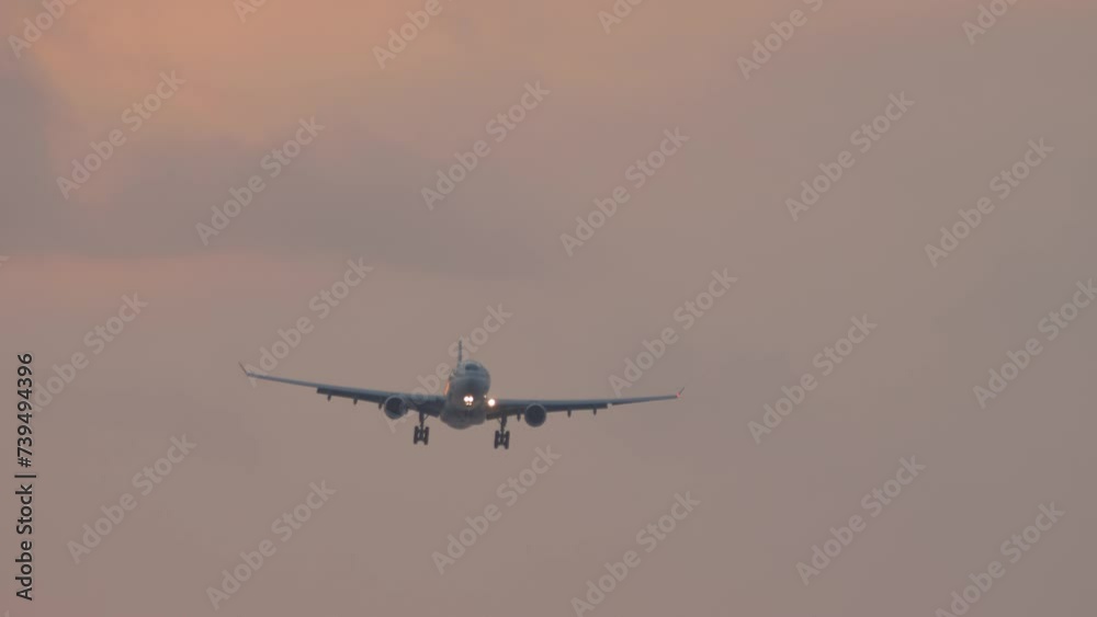 Jet plane with unrecognizable livery approaching landing in pink sunset Jet plane with unrecognizable livery approaching landing in pink sunset