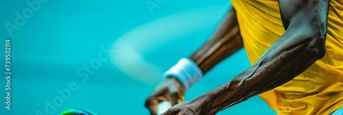 Photo of a tennis player's arm, strong, muscles, sweat, tight grip on the racket handle, blue and yellow 