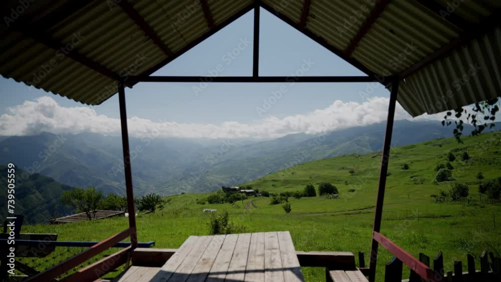 Green hills and distant peaks seen from under a tin roof.Mountain View from Rustic Wooden Shelter Green hills and distant peaks seen from under a tin roof.Mountain View from Rustic Wooden Shelter