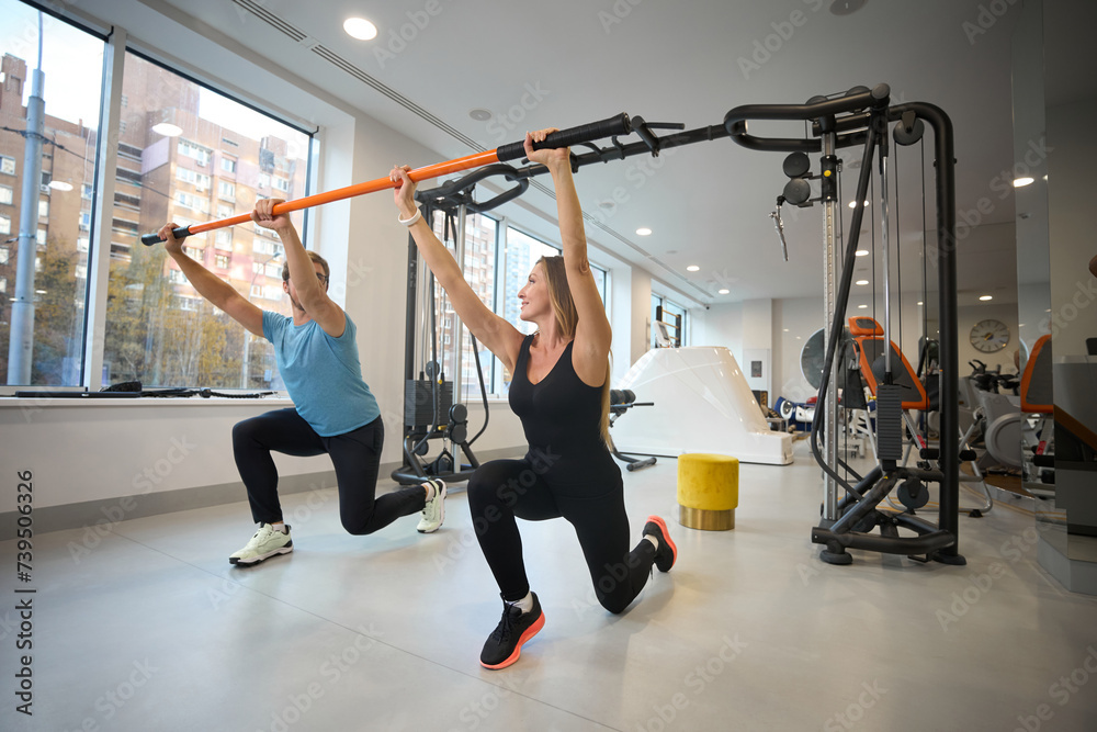 Fototapeta premium Middle-aged woman and man are doing warm-up with special stick