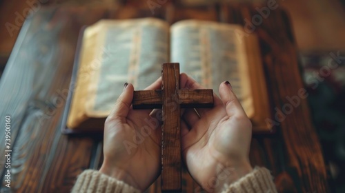 A woman who believes in a higher power is pictured holding a wooden cross on an open holy bible