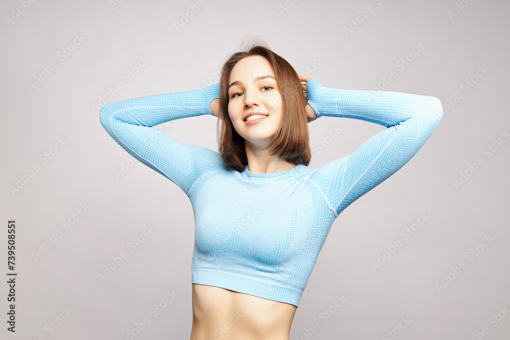 a beautiful girl in a tracksuit smiles on a gray background, copy space a beautiful girl in a tracksuit smiles on a gray background, copy space