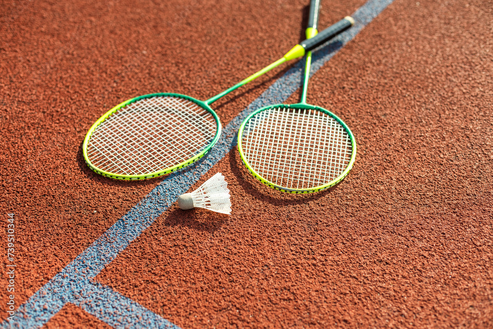 Badminton rackets and feather shuttlecock on the court
