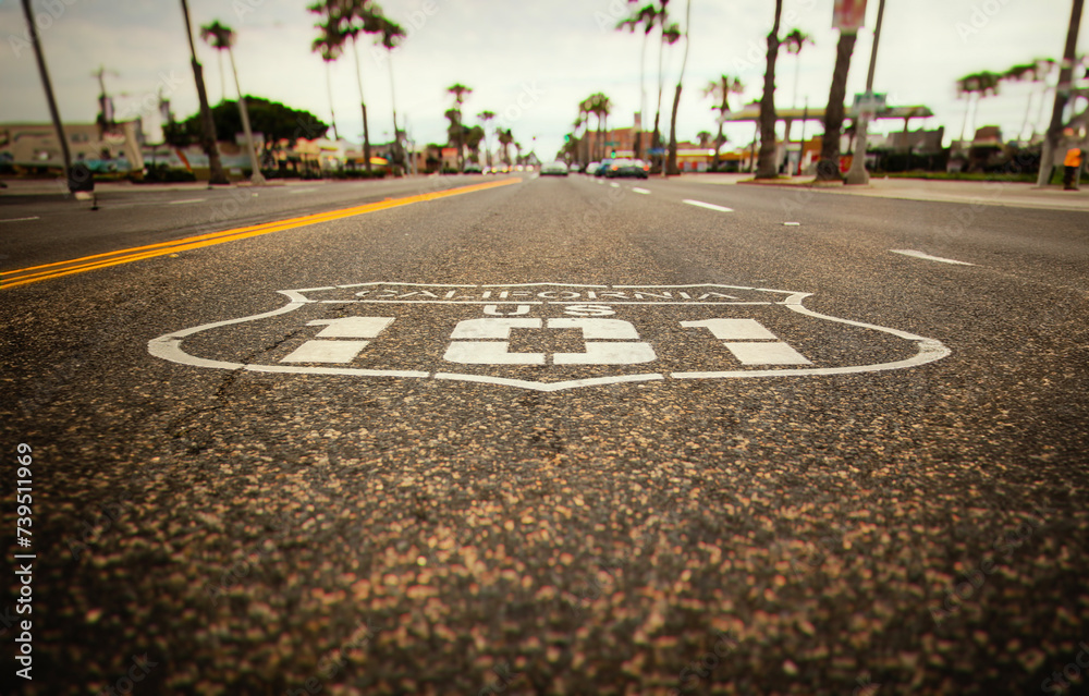 Obraz premium Highway 101 sign painted on the black asphalt road with city diffused in the background. The shot is from Oceanside California