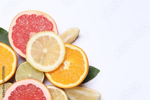 Fototapeta Naklejka Na Ścianę i Meble -  Different cut citrus fruits on white table, flat lay. Space for text