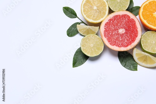 Fototapeta Naklejka Na Ścianę i Meble -  Different cut citrus fruits and leaves on white table, flat lay. Space for text