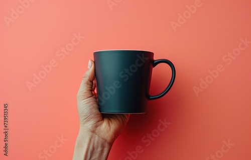 black coffee cup held up against the pink wall