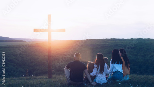 Crucifixion cross. People near the cross. Christian family around a wooden cross. Calvary and Easter. Jesus' resurrection and death.