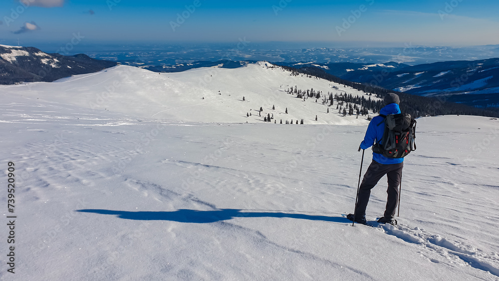Man in snowshoes on snow covered mountains of Kor Alps, Lavanttal Alps, Carinthia Styria, Austria. Winter wonderland in Austrian Alps. Ski touring and snow shoe tourism. Tranquil serene atmosphere