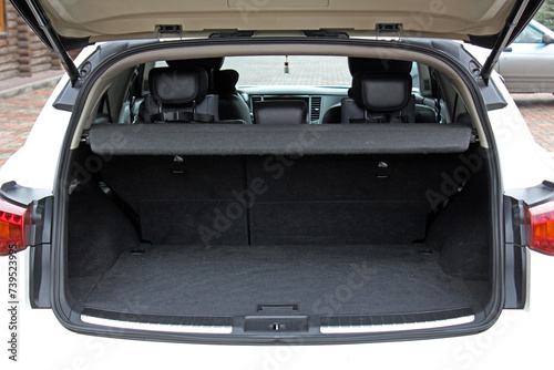 White lux SUV open trunk. Open empty trunk in the modern SUV. Car boot space shot. Modern SUV open trunk. Ready for luggage loading. Front view.