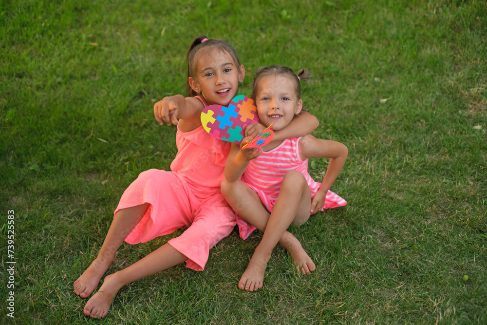 A child with a colorful puzzle card hugs the autism sister and points his finger at the camera