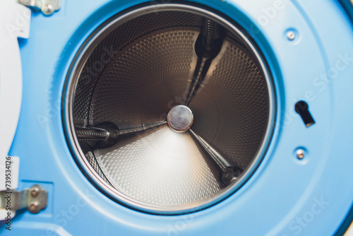 white washing machine door in landromat, with an empty inner drum in blue tint. photo