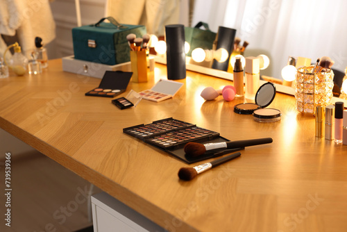 Different cosmetic products on wooden dressing table in makeup room