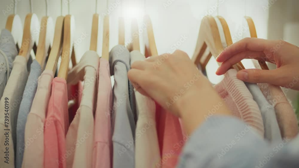 A sale is taking place in bright store stylish woman, dressed in oversized clothes, gently flips through the goods on the hangers. The modern girl follows fashion trends trends when choosing clothes A sale is taking place in bright store stylish woman, dressed in oversized clothes, gently flips through the goods on the hangers. The modern girl follows fashion trends trends when choosing clothes