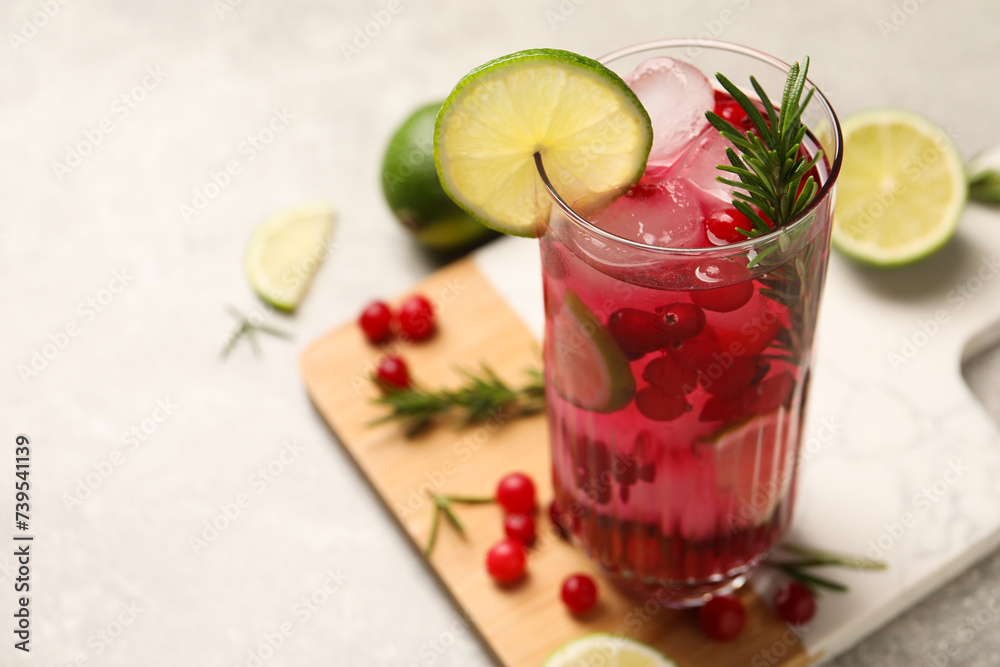 Tasty cranberry cocktail with rosemary and lime in glass on gray table, closeup. Space for text Tasty cranberry cocktail with rosemary and lime in glass on gray table, closeup. Space for text