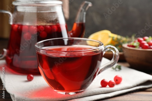 Tasty hot cranberry tea in glass cup and fresh berries on wooden table