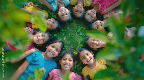Group of happy Indian kids standing in circle together looking up at the camera in the summer park  Playful asian children together at outdoor garden. View from above. Background