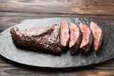 Pieces of delicious grilled beef meat on wooden table, closeup