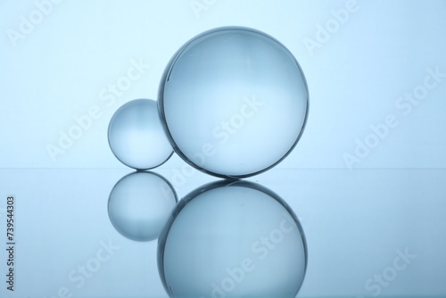 Transparent glass balls on mirror surface against light background