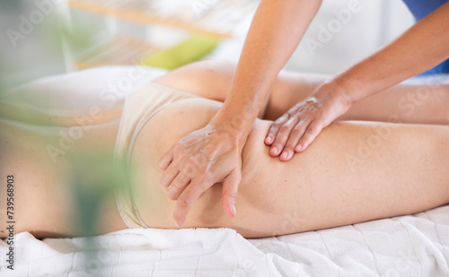Young woman gets intensive anti-cellulite massage of buttocks on couch
